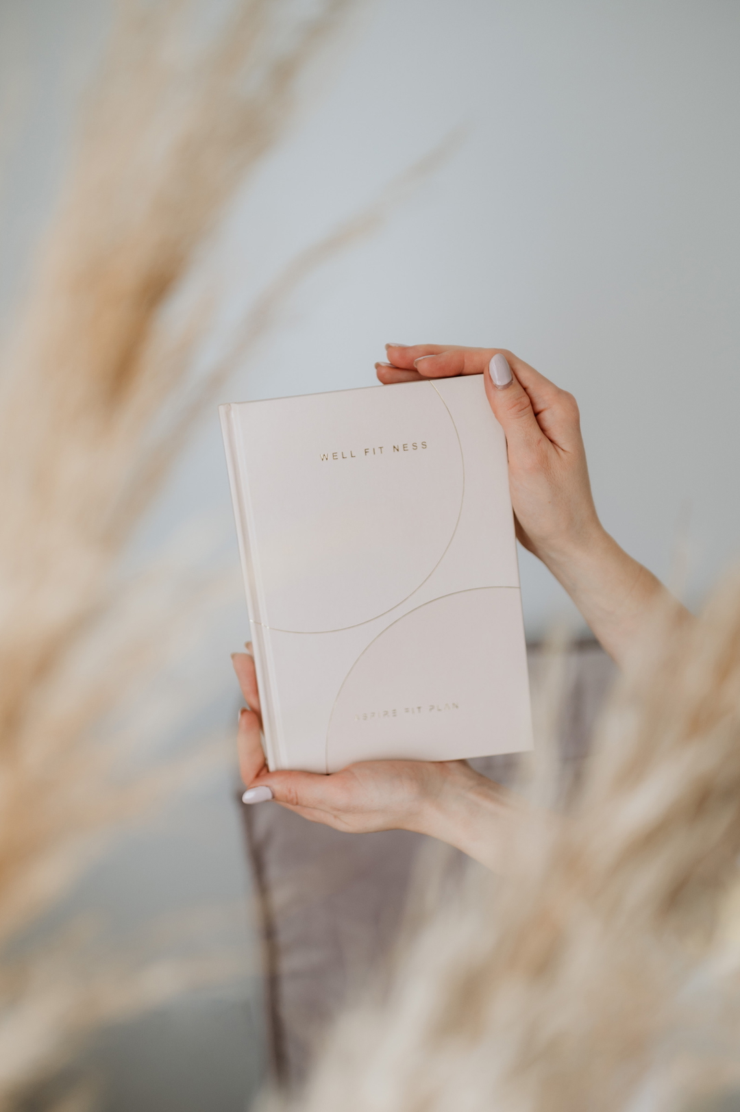 Hands holding a wellness planner with the words Well Fitness and Inspire Fit Plan on the cover.
