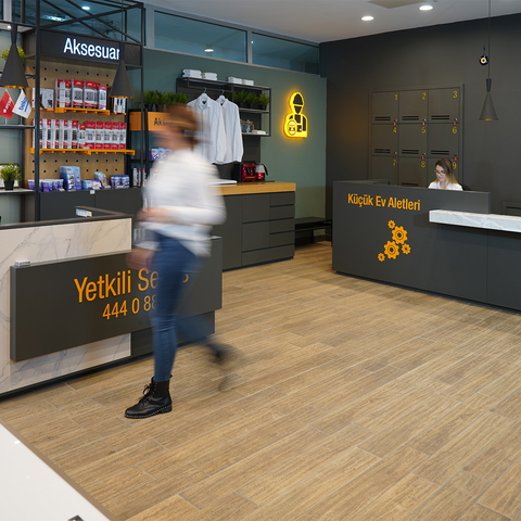 The interior of a modern retail store with a receptionist, displays, and blurred customer.