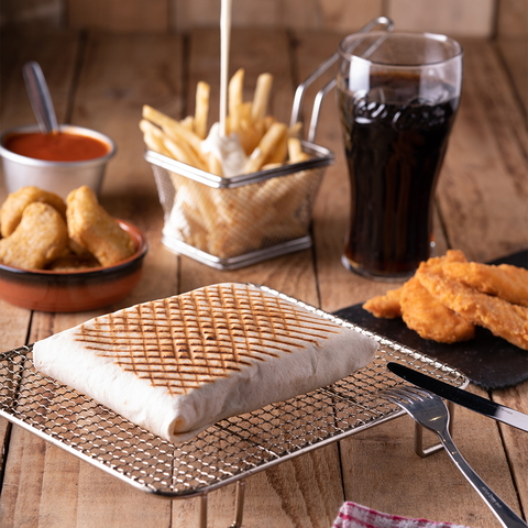 A close-up captures a grilled tacos, fries, chicken nuggets, and soda on a wooden table.