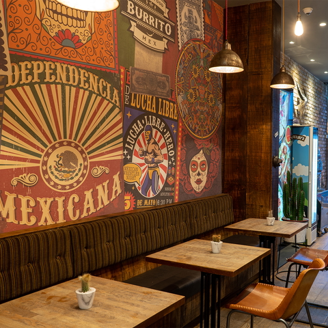 A vibrant Mexican restaurant interior features colorful wall art and cozy seating for a unique dining experience.