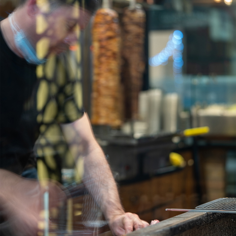 A man prepares shawarma at a restaurant, captured with a shallow depth of field.