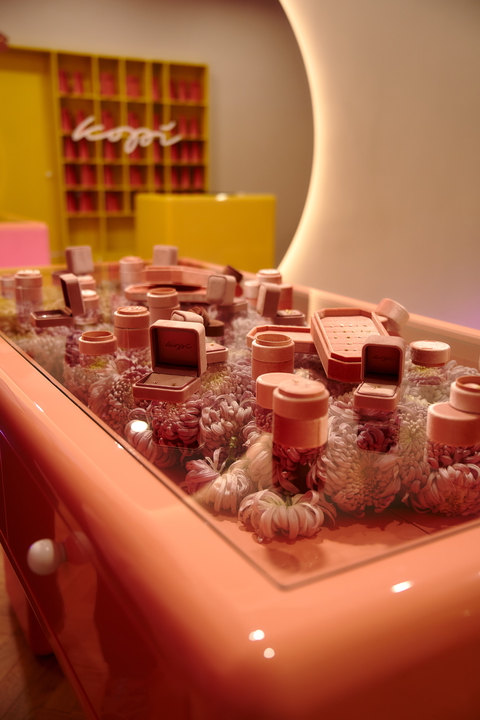 Close-up shot of jewelry cases and white flowers inside a peach-colored glass display, creating an elegant and dreamy scene.
