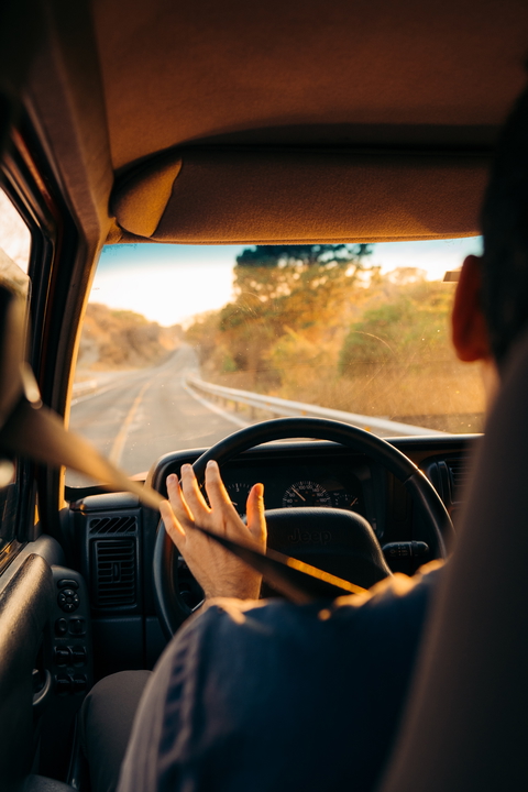 A person driving a jeep on a road trip during golden hour.