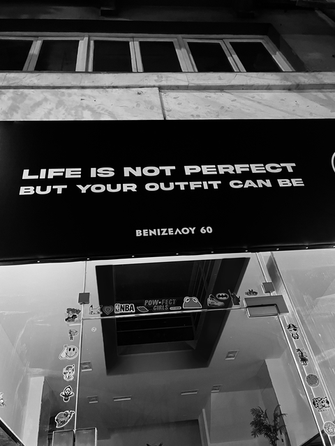 A storefront sign that says, "Life is not perfect, but your outfit can be" for marketing and promotion.