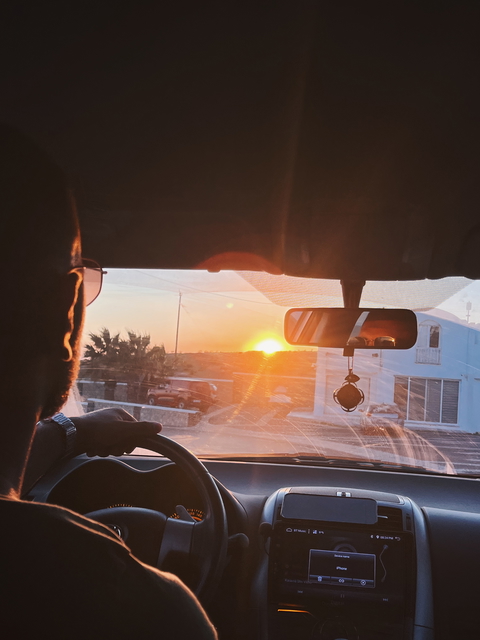 Man driving a car at sunset, capturing a moment of calm during a road trip.