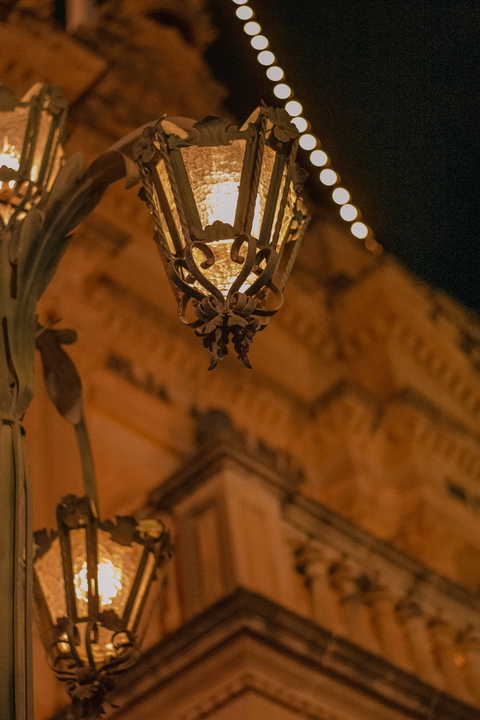 A vintage street lantern glows softly at night, casting a warm, dreamy light.