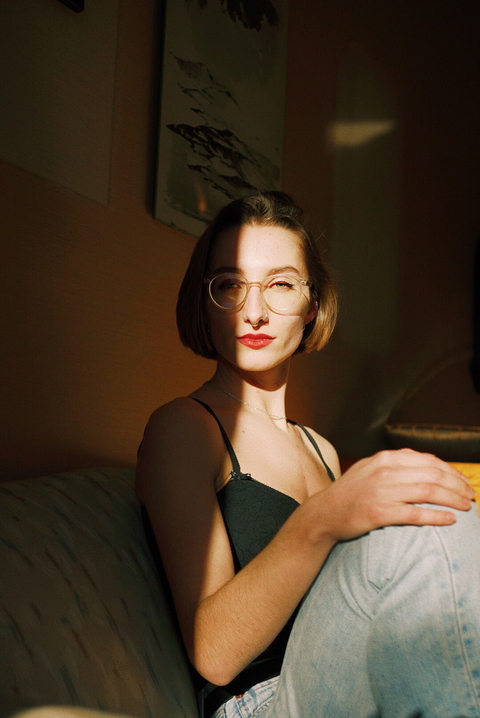 Portrait of a young woman wearing glasses in soft, natural light, creating a dreamy and intimate atmosphere.