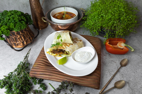 A delicious burrito with lime and sauce presented in a close-up food photograph.
