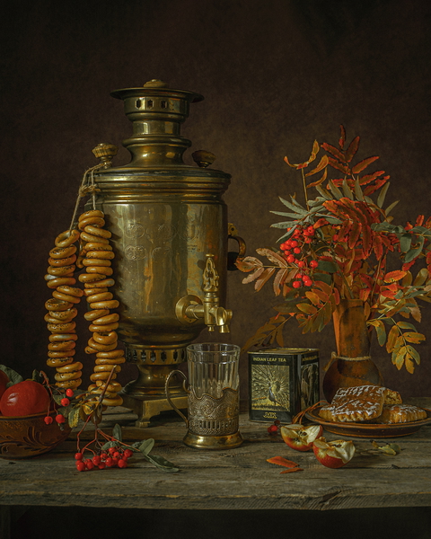 A vintage still life featuring a samovar, bagels, apples, cookies, and rowan berries on a rustic wooden table.
